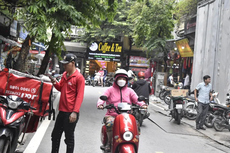 A street in Hanoi's Old Quarter with scooters and cafe signboards